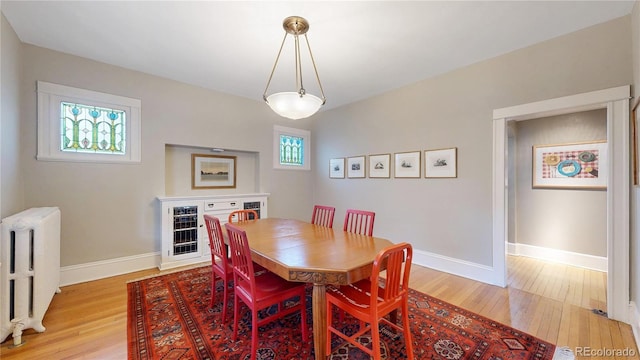 dining room featuring radiator heating unit, baseboards, and light wood-style flooring