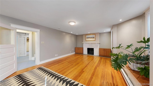 living area featuring recessed lighting, a brick fireplace, baseboards, and light wood finished floors