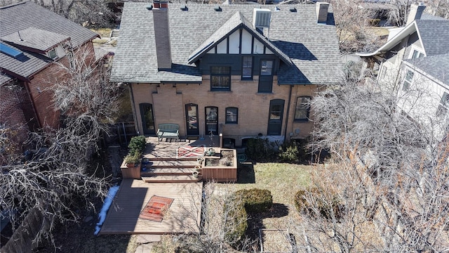 view of front of home featuring a shingled roof, brick siding, a patio, and a chimney