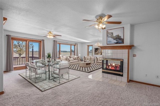 carpeted dining space with a tiled fireplace, a textured ceiling, and ceiling fan