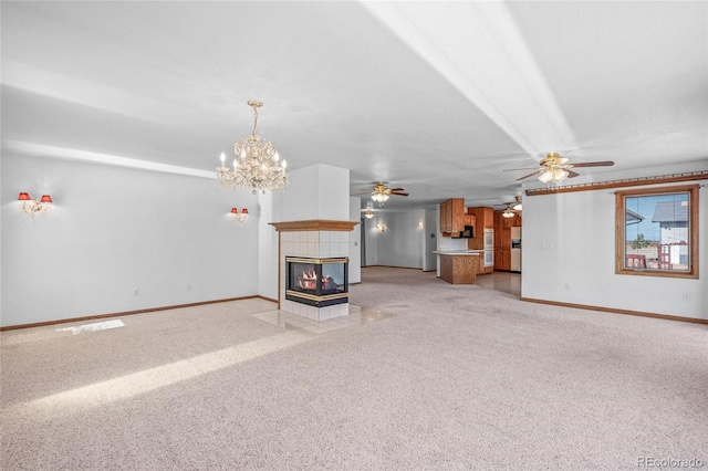 unfurnished living room with a tiled fireplace, light colored carpet, and a chandelier