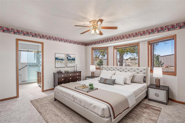 carpeted bedroom featuring multiple windows, a textured ceiling, connected bathroom, and ceiling fan