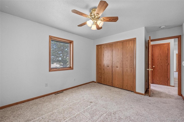 unfurnished bedroom with light carpet, a textured ceiling, a closet, and ceiling fan