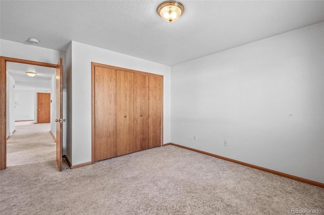 unfurnished bedroom featuring a closet, light carpet, and a textured ceiling