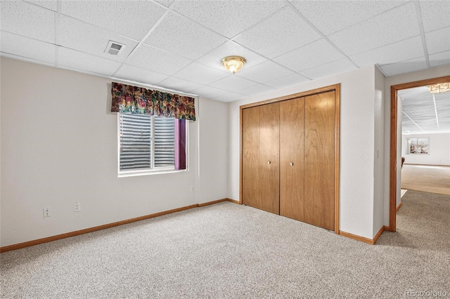 unfurnished bedroom with carpet flooring, a closet, and a paneled ceiling