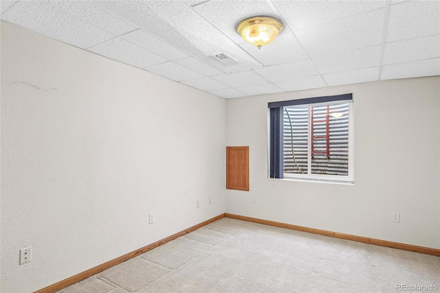 carpeted empty room with a paneled ceiling