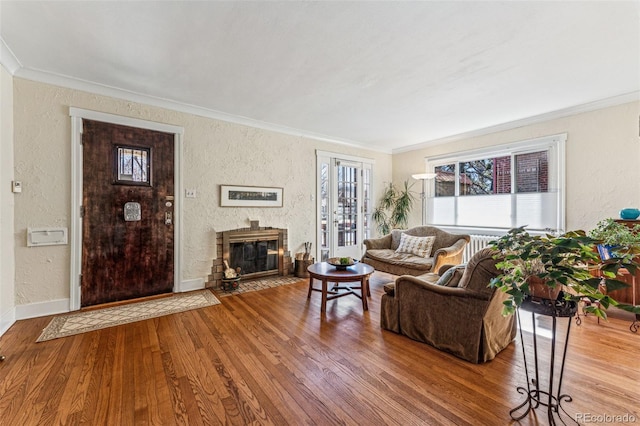 living room with baseboards, ornamental molding, wood finished floors, and a textured wall