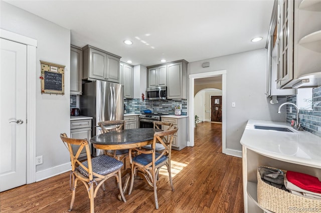 kitchen featuring appliances with stainless steel finishes, arched walkways, a sink, and gray cabinetry