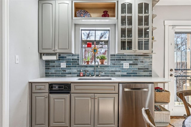 kitchen featuring a sink, glass insert cabinets, light countertops, and dishwasher