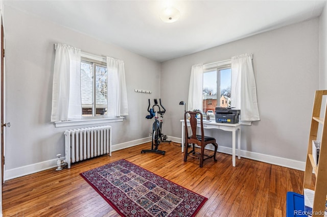 office space with a healthy amount of sunlight, radiator heating unit, baseboards, and wood-type flooring