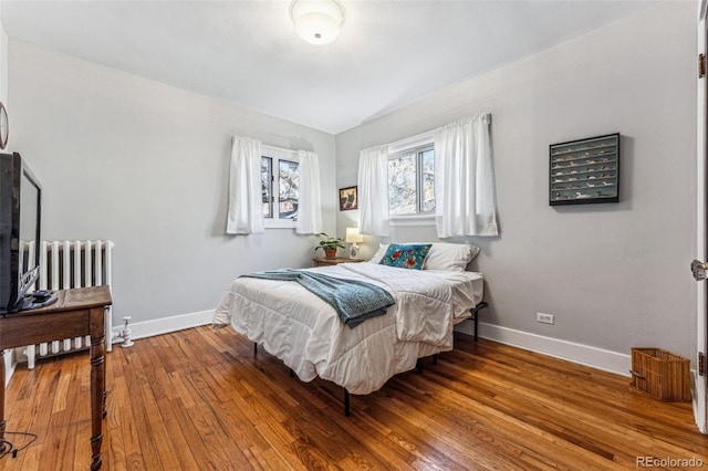 bedroom featuring radiator heating unit, baseboards, and wood-type flooring