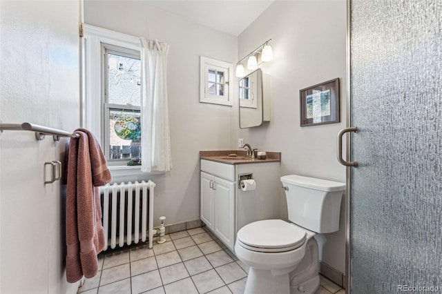 bathroom with tile patterned flooring, toilet, vanity, baseboards, and radiator