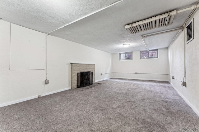 basement featuring carpet floors, a fireplace, a textured ceiling, and baseboards