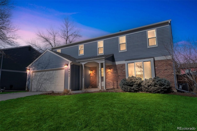 traditional-style home featuring a garage, driveway, brick siding, and a front lawn