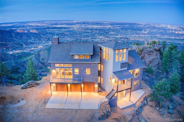 exterior space featuring a patio area, a garage, a chimney, stucco siding, and stairs