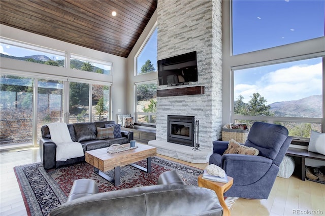 living area featuring a mountain view, wooden ceiling, a fireplace, wood finished floors, and high vaulted ceiling