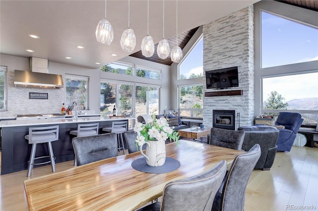 dining room with high vaulted ceiling, light wood finished floors, recessed lighting, and a fireplace