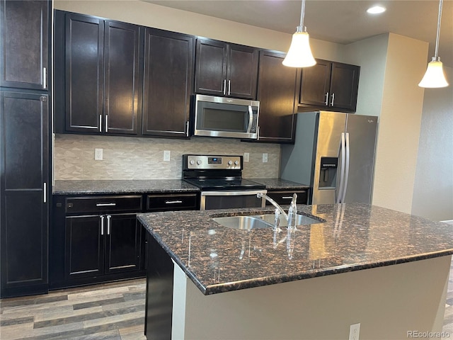 kitchen with appliances with stainless steel finishes, decorative backsplash, a sink, and light wood-style flooring