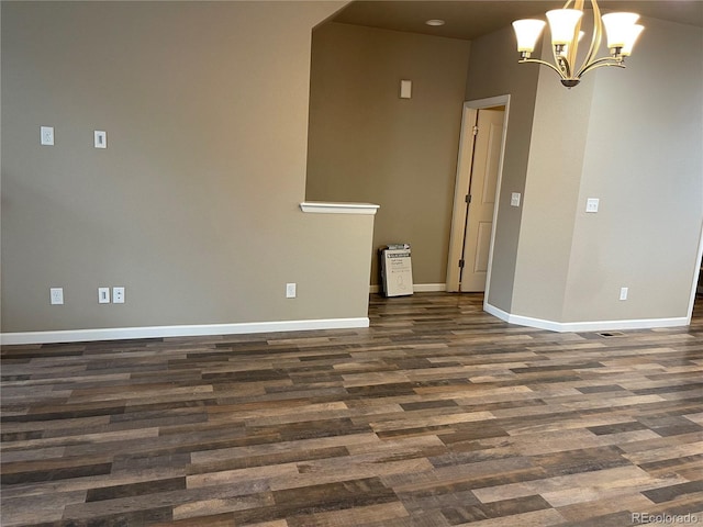 unfurnished room featuring baseboards, dark wood-style floors, and a notable chandelier