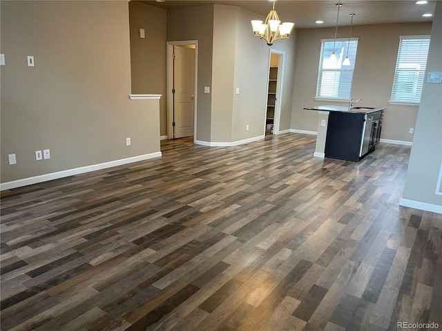 unfurnished dining area featuring baseboards, recessed lighting, dark wood finished floors, and an inviting chandelier