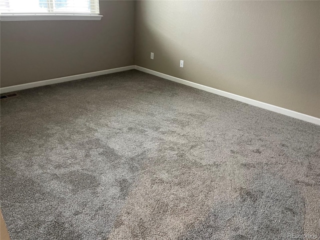 carpeted spare room featuring baseboards and visible vents