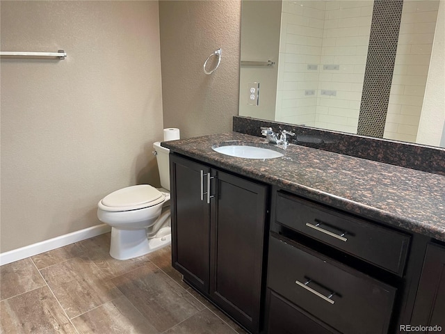 bathroom with toilet, baseboards, wood finished floors, and vanity