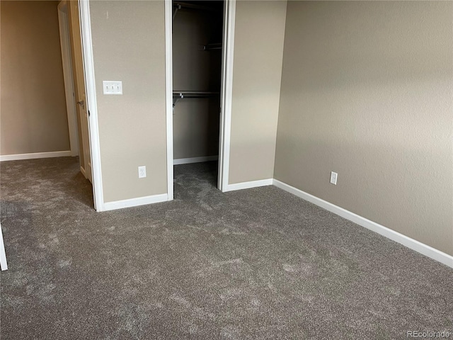 unfurnished bedroom with baseboards, carpet, a closet, and a spacious closet
