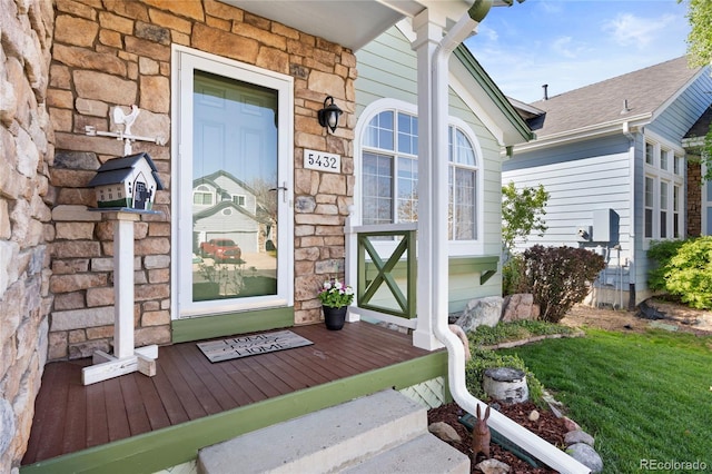 entrance to property with a shingled roof and stone siding