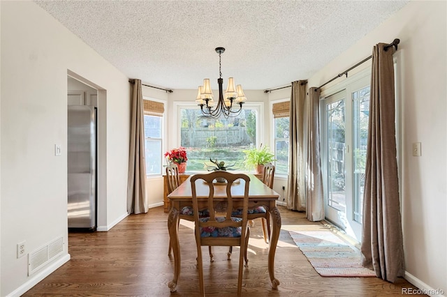 dining area featuring plenty of natural light, visible vents, a textured ceiling, and a notable chandelier