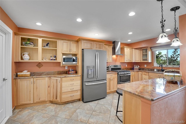 kitchen with pendant lighting, wall chimney exhaust hood, stainless steel appliances, light brown cabinets, and light stone countertops