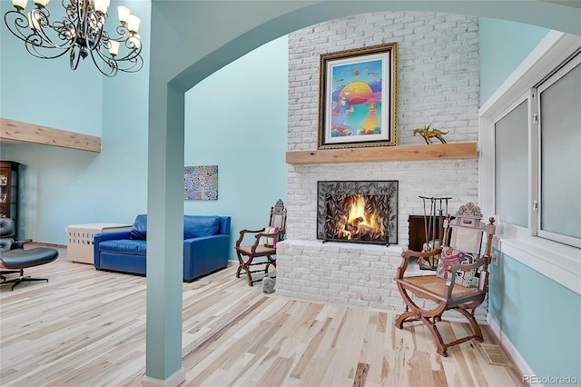 interior space with a brick fireplace, light wood-type flooring, and a notable chandelier