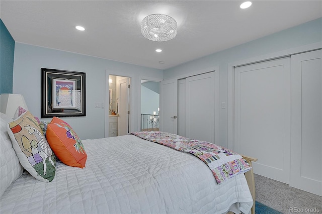 bedroom with connected bathroom, carpet flooring, and two closets