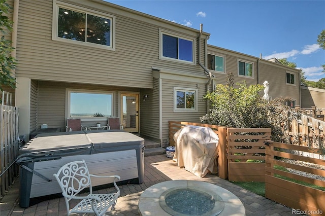 rear view of property with a hot tub, a patio area, and a fire pit