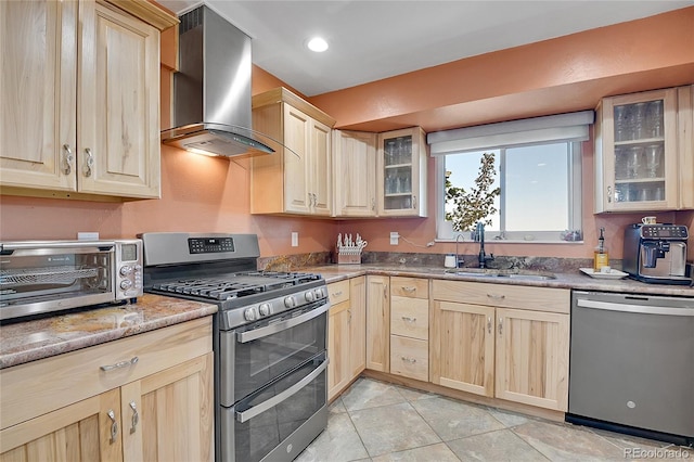 kitchen with light brown cabinets, light tile patterned flooring, sink, wall chimney range hood, and stainless steel appliances