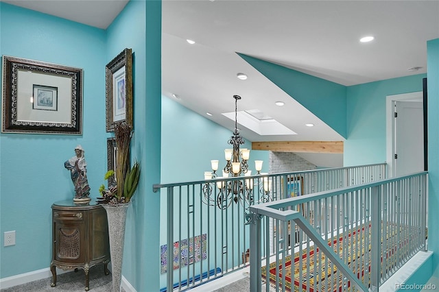 corridor with a notable chandelier, carpet, and a skylight