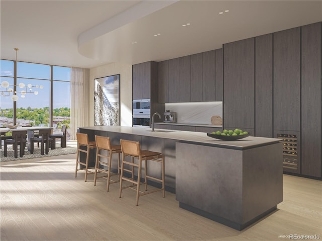 185 Steele St Unit 408, Denver, CO 80206 - kitchen with modern cabinets, a kitchen bar, light wood-style flooring, a wall of windows, and a chandelier