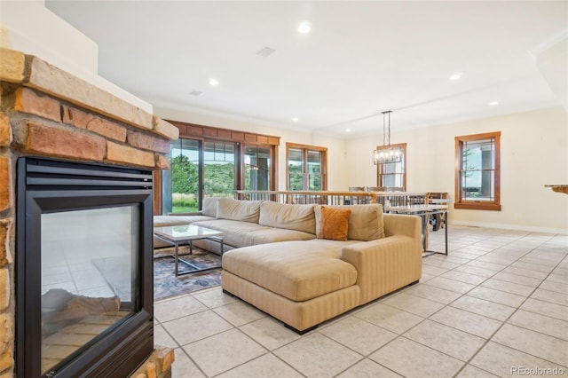 tiled living room featuring crown molding, a fireplace, and a chandelier