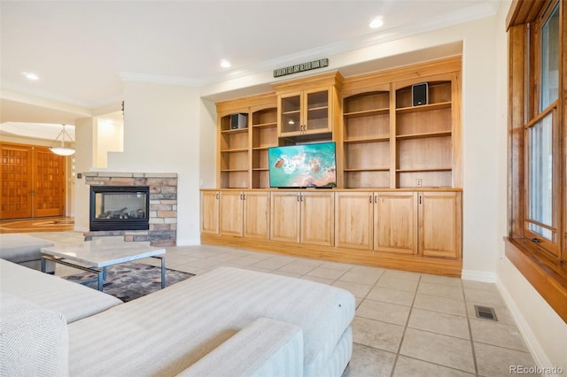 tiled living room with ornamental molding and a stone fireplace