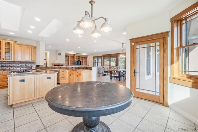 kitchen with light brown cabinetry, a chandelier, kitchen peninsula, and decorative backsplash