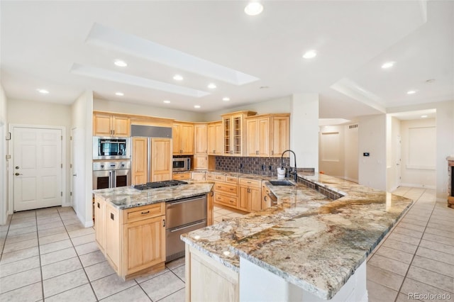 kitchen featuring built in appliances, light stone countertops, tasteful backsplash, a center island, and light brown cabinets