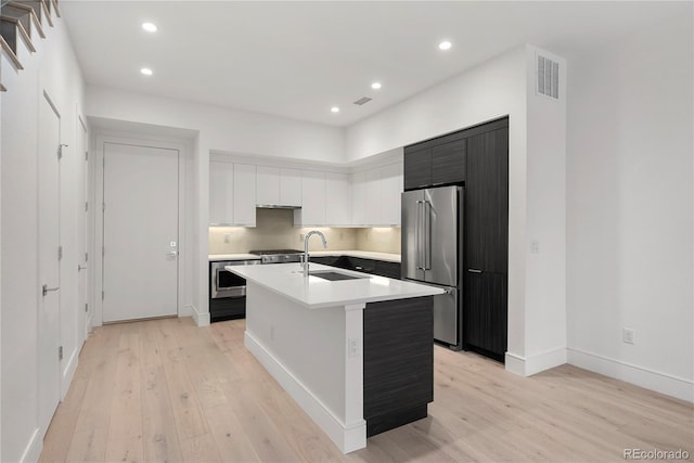 kitchen featuring sink, high end refrigerator, light wood-type flooring, an island with sink, and white cabinets