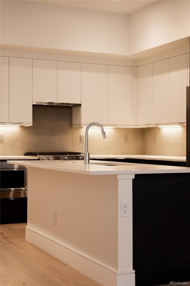 kitchen with white cabinetry, light hardwood / wood-style flooring, and decorative backsplash