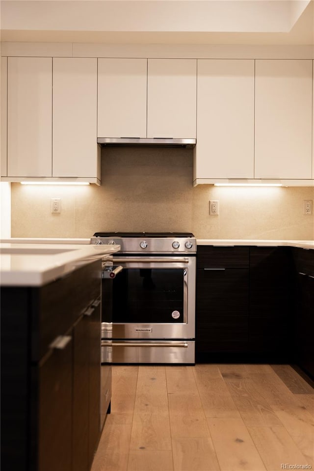 kitchen with white cabinets, stainless steel range oven, and light hardwood / wood-style flooring