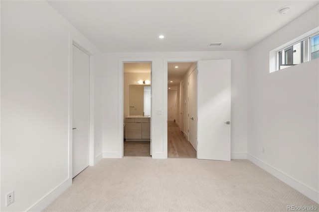 unfurnished bedroom with connected bathroom and light colored carpet