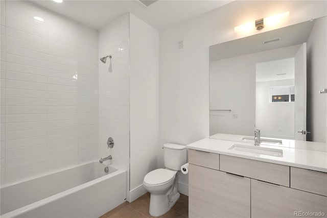 full bathroom with tile patterned flooring, vanity, tiled shower / bath combo, and toilet