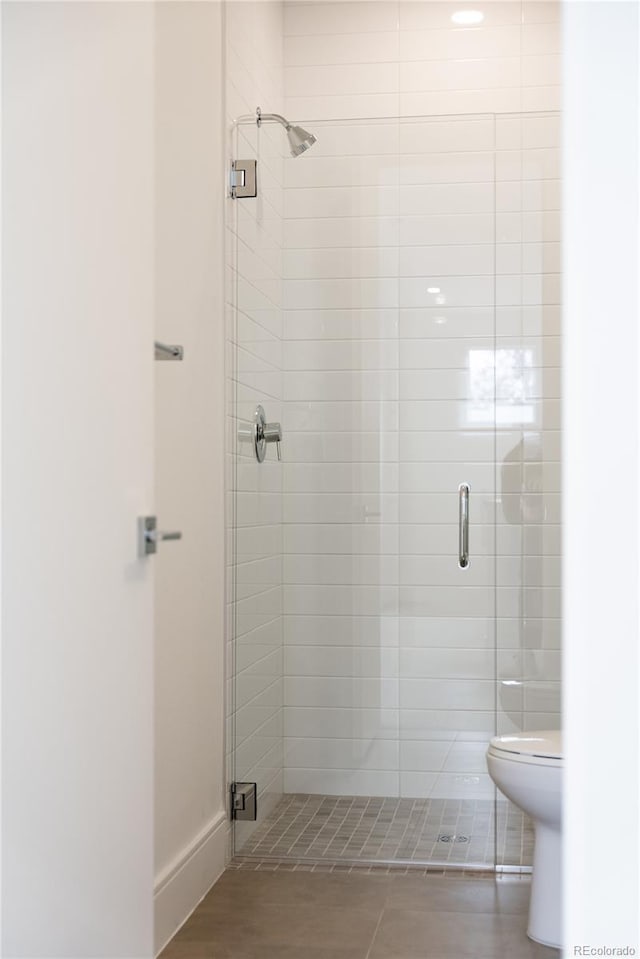 bathroom with tile patterned floors, toilet, and an enclosed shower