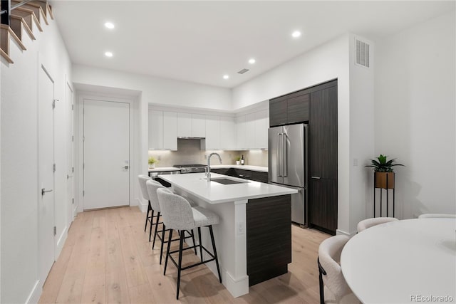 kitchen with visible vents, a sink, light countertops, a kitchen breakfast bar, and high quality fridge