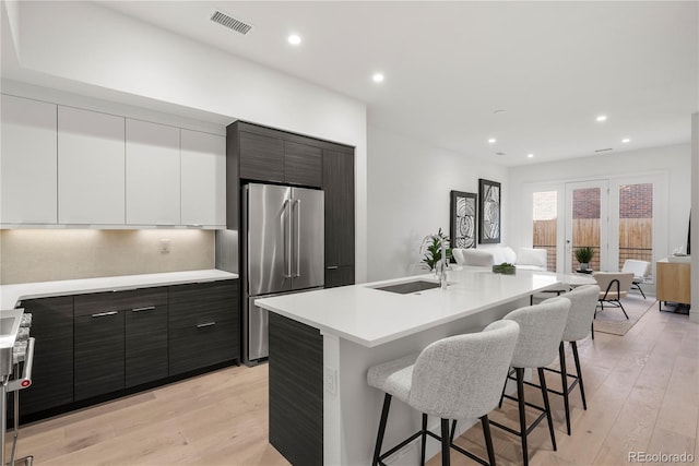 kitchen with visible vents, a breakfast bar, a sink, high quality fridge, and open floor plan