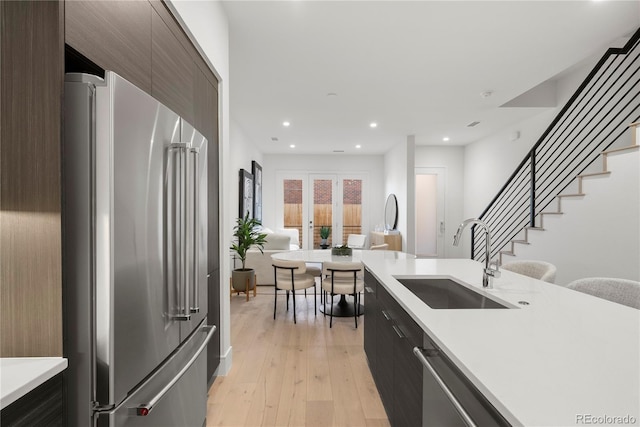 kitchen with stainless steel appliances, modern cabinets, light countertops, and a sink