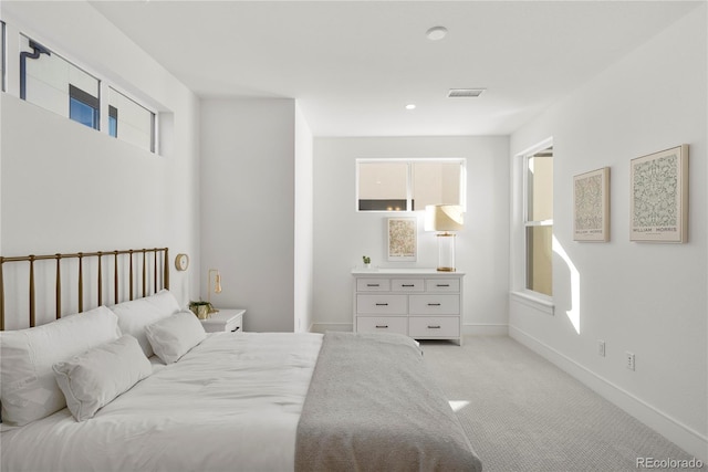 bedroom featuring visible vents, light colored carpet, and baseboards